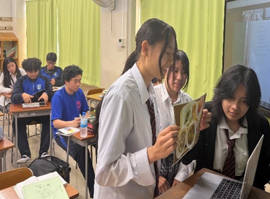 カメラに向かって絵を手に説明する生徒