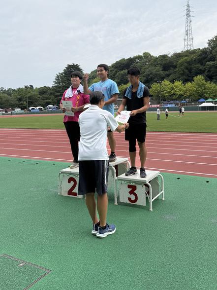 表彰台で3位入賞の賞状をもらう陸上競技部員2