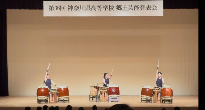 発表会のステージで高く腕を上げて和太鼓をたたく様子