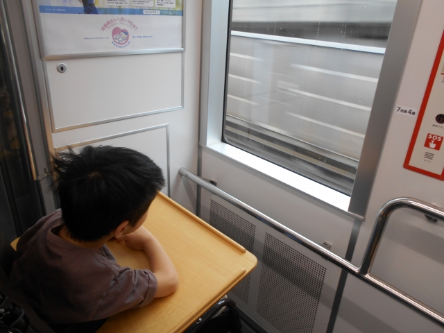 電車の窓をのぞいて景色を見ているところ